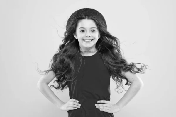 Volumen de pelo. Niña en sombrero de estilo francés. chica feliz con el pelo rizado largo en boina. infancia. peluquería. belleza de la moda de verano. niño parisino sobre fondo amarillo. concepto de volumen de cabello —  Fotos de Stock