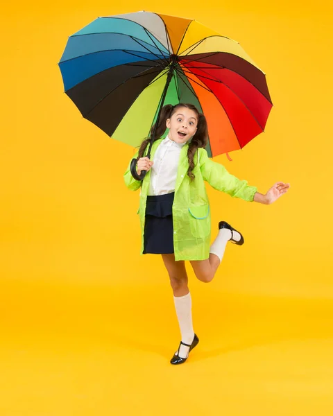 Forecast application. Positivity concept. Rainy day fun. Happy walk under umbrella. Rain concept. Kid girl happy hold colorful rainbow umbrella. Rainy weather garments. Good mood. Smiling kid