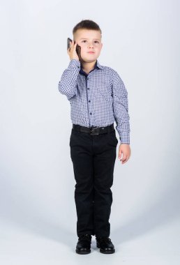 Modern bir alet. Küçük işadamı. İşletme. Yetiştirme ve geliştirme. Küçük çocuk resmi kıyafetler cep telefonunu arıyor. Şirin çocuk akıllı telefonu tut. Gezici konuşma. Mobil iletişim