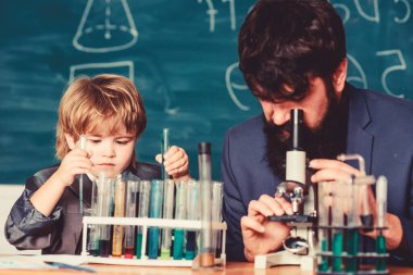 Bilim adamının elinde deney tüpleriyle matara. Bilgelik. Okula dönelim. Küçük çocuk ve öğretmen adam. Oğlu ve babası okulda. Tahtalı eğitim odası. Eğitim özgürlüğün üstün bir kalkanıdır..