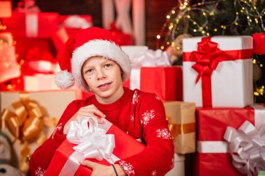 İlgi çekici şirin Noel Baba. Küçük mutlu çocuk Noel ağacının yanında hediyeler bulur. Hediyelik eşya dükkanı. Çocuk Noel Baba şapkası hediye kutuları. Mutlu noeller. Kışın güzelliği. Boş zaman ve aktivite. Boks günü