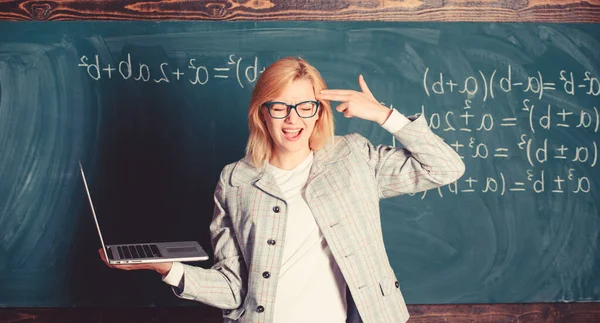 Educador inteligente inteligente dama con portátil moderno sostener gesto pistola en su fondo pizarra cabeza. Profesora cansada molesta por su trabajo. Mujer cansada o molesta sostiene portátil. Concepto de reformas educativas — Foto de Stock