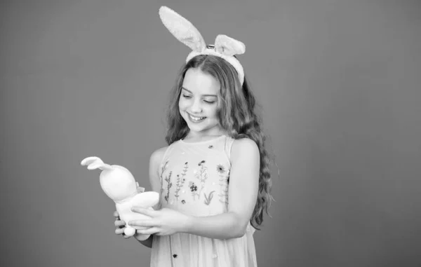 Bleiben Sie ruhig und frohe Ostern. kleines Mädchen und Kaninchen Spielzeug. kleines Mädchen in Hasenohren mit Osterspielzeug. Kleines Kind im Osterhasenstil beim Spielen mit Spielzeug. kleines Kind mit süßem Spielzeug. Osterhase — Stockfoto