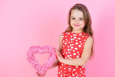 Mutlu kız pembe arka planda pembe kalbi tutar