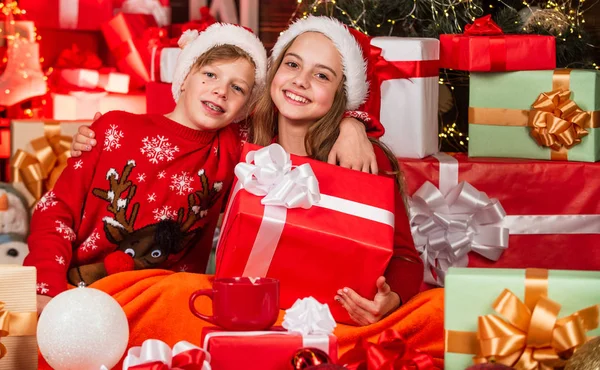 Freunde kleiner Kinder haben ihren Spaß. Weihnachtsmann-Helfer inmitten roter Geschenkboxen. Zu viele Geschenke. Online-Shopping. Kinderglück und Unbekümmertheit. Familienwerte für Kinder. gemütlicher Winterabend zusammen — Stockfoto
