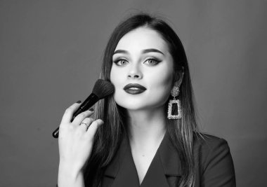 Makyöz konsepti. İyi görünüyorsun ve kendine güveniyorsun. Göz kamaştırıcı makyaj kırmızısı dudaklar. Moda model TV sunucusu. Makyaj fırçası kullanan çekici bir kadın. Tüm kusurları gizlemek. Mükemmel ten rengi