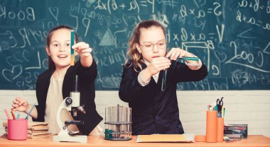 Küçük bilim adamı mikroskop ile çalışıyor. Okul laboratuarında küçük kızlar. Kimya eğitimi. Biyoloji dersi. Kimya araştırması. Kimya laboratuvarında bilim deneyleri. Amacımız tedaviyi bulmak.