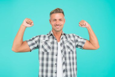 Yapabilirim. Güçlü adam mavi arka planı. Kaslı adam kollarını esnetir. Sıradan tarzda yakışıklı bir adam. Beyaz adam güç gösterisi yapıyor. Moda ve tarz. Spor ve spor salonu. Antrenman ve antrenman