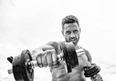 Kazanmak alışkanlıktır. Başarı seçimdir. Halter egzersiz salonu. Dambılla egzersiz icra eden kaslı bir adam. Güçlü gövdeli sporcu. Spor ekipmanları. Fitness ve vücut geliştirme sporu. Spor yaşam tarzı