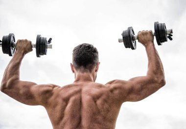 Eylemler koçlardan daha yüksek sesle konuşur. Sırtı ve kolları güçlü bir sporcu. Spor malzemeleri. Vücut geliştirme sporu. Spor yaşam tarzı. Aptal egzersiz salonu. Dambıl gibi arkadan bakan kaslı bir adam.