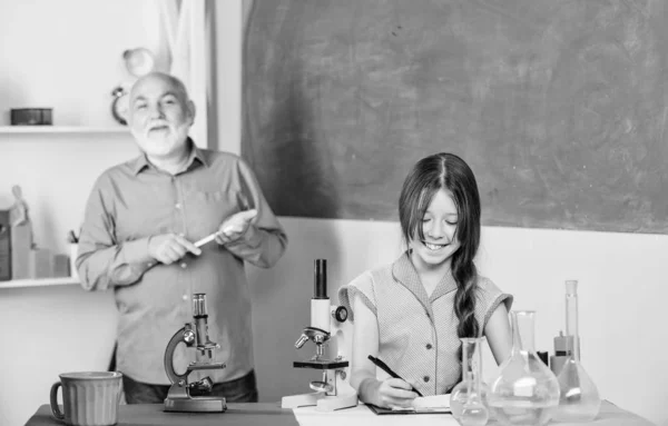 A verificar os resultados. professor maduro de biologia. Aluna no laboratório da escola. Microscopia. Equipamento de laboratório. usar lupa. aula de ciências. menina pequena com homem tutor estudar química — Fotografia de Stock