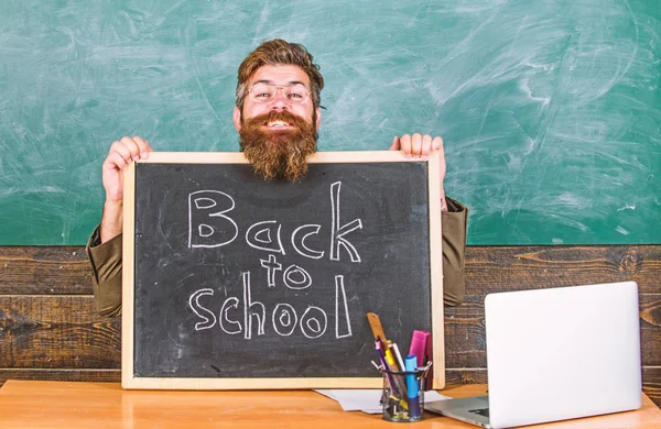 Teacher or school principal welcomes with blackboard inscription back to school. Welcome back. Beginning of new school year in september. Teacher welcomes new pupils to enter educational institution