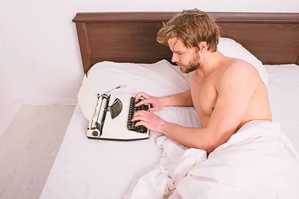 Man writer lay on bed white bedclothes working on new book. Morning inspiration concept. Guy create new chapter use typewriter. Writer author used to old fashioned machine instead of digital gadget