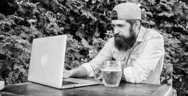 Usando a nova tecnologia. Homem barbudo a comunicar através da tecnologia de comunicação. Hipster bebendo cerveja e usando a tecnologia laptop no café ao ar livre. Continuando produtivo com a tecnologia de computador — Fotografia de Stock