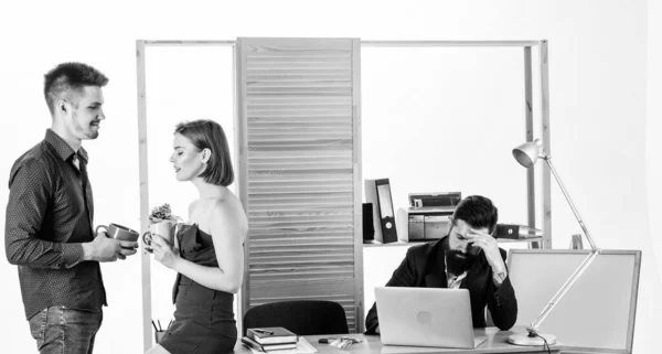 Employee break. Business partners enjoying conversation in lunch break while colleague working in background. Two coworkers having tea or coffee break. Young managers talking during work break