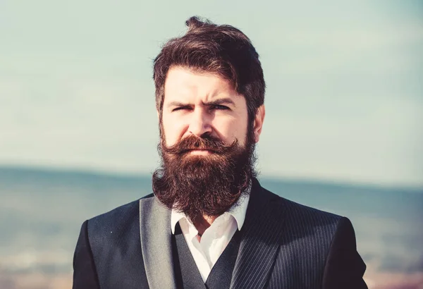 Man bearded hipster wear formal suit blue sky background. Vintage style long beard. Facial hair beard and mustache care. Beard fashion trend. Invest in stylish appearance. Grow thick beard fast