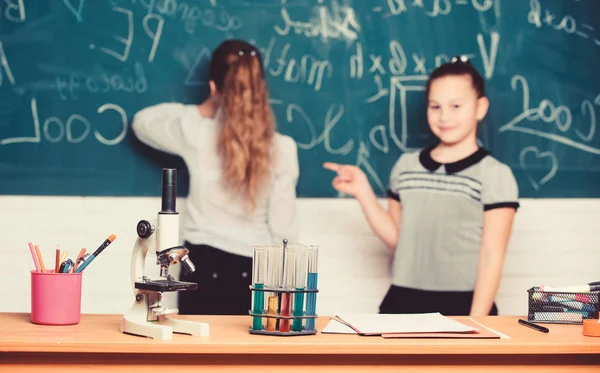 Chemische reacties. Maak het bestuderen van chemie interessant. Leerling op schoolbord op scheikunde les. Educatief experiment concept. Meisjes klasgenoten studeren chemie. Microscoop en reageerbuisjes op tafel — Stockfoto