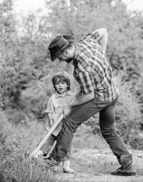 Охота за сокровищами. Маленький помощник работает в саду. Милый ребенок в природе веселится с лопатой. Найти сокровища. Мальчик и отец с лопатой ищут сокровища. Счастливого детства — стоковое фото