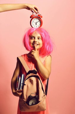 Okul üniformalı, başında peruk ve alarm olan bir öğrenci.