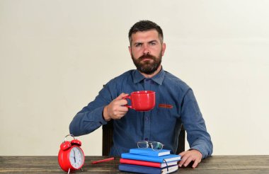 Retro saat, gözlükler ve masada kırmızı ve mavi kitaplar.