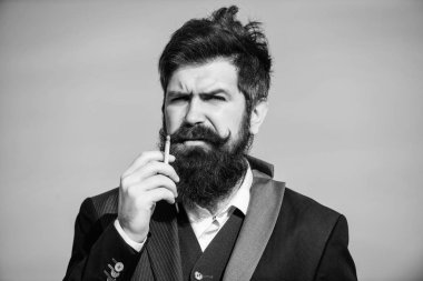 Sakallı hipster sigara mavi gökyüzü arka plan sigara. Sigaralı adam nikotin etkisinin tadını çıkarıyor. Sigara içmenin zevki. Rahatlatıcı ama zararlı alışkanlık. Sakallı ve bıyıklı adam sigara tutuyor