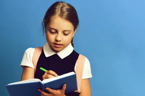 Menina da escola com expressão facial diligente no fundo azul — Fotografia de Stock