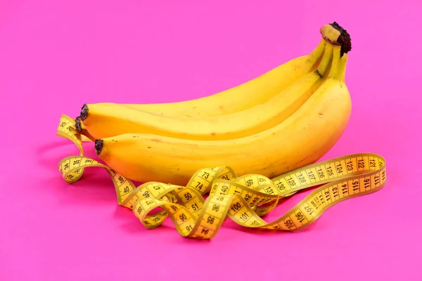Taśma do pomiaru w kolorze żółtym w pobliżu trzech bananów — Zdjęcie stockowe