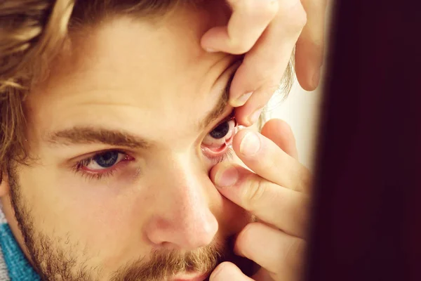 Homem com barba e olhos azuis coloca lentes de contato — Fotografia de Stock