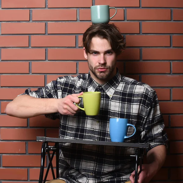 Chico guapo sosteniendo tazas sobre fondo de pared de ladrillo — Foto de Stock