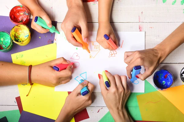 Markers in mannelijke en vrouwelijke handen tekenen op wit papier — Stockfoto