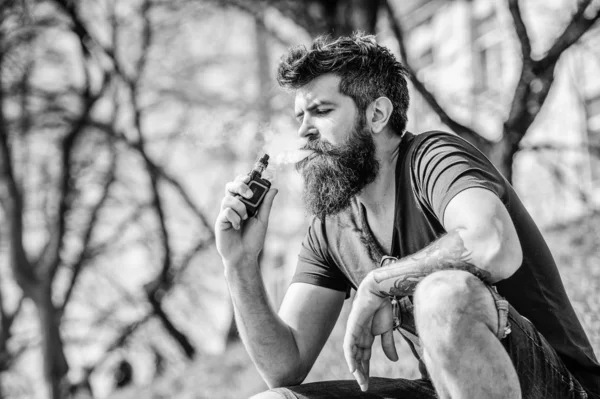 Курящее устройство. Мужчина с длинной бородой, расслабленный от курения. Человек с бородой выдыхает дым. Облака ароматизированного дыма. Концепция снятия стресса. Бородатый человек курит вапе. Курение электронных сигарет — стоковое фото