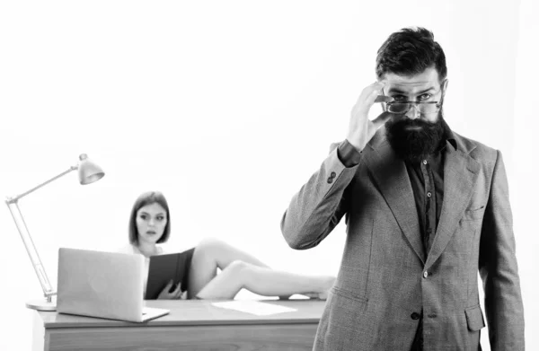 Έξυπνος και όμορφος άντρας. Έξυπνος άντρας που κοιτάει μέσα από γυαλιά με σέξι γυναίκα που δουλεύει στο παρασκήνιο. Ένας γενειοφόρος άντρας με έξυπνο, καθημερινό ντύσιμο με συνάδελφο. Έξυπνος επιχειρηματίας και όμορφη γραμματέας στο γραφείο — Φωτογραφία Αρχείου