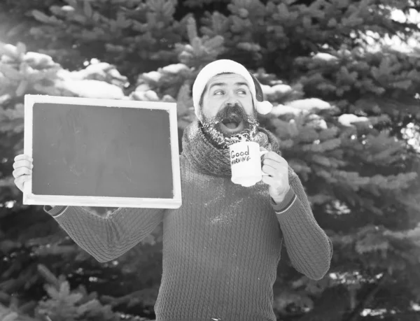 Homem santa com quadro branco e copo de café dia de inverno ao ar livre no fundo natural, espaço de cópia — Fotografia de Stock