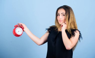 Zaman yönetimi. Dakiklik ve disiplin. Kadının elinde kırmızı alarm saati var. Sürenin dolmasına kadar zaman sayıyorum. Güzel kız zamanını yönetiyor. Fazla çalışmak ya da geç kalmak. Zamanlama sorunu. Vakit geldi. Birkaç dakika.