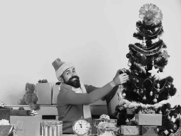 Papai Noel decora árvore de Natal. Papai Noel senta-se perto de abeto — Fotografia de Stock