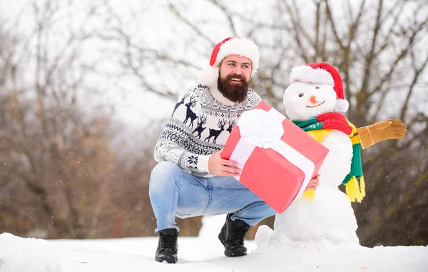 Christmas vacation. man give present outdoor. happy hipster ready for xmas. bearded man build snowman. Happy new year. winter holiday. warm sweater in cold weather. winter season. Merry christmas — Stock Photo, Image