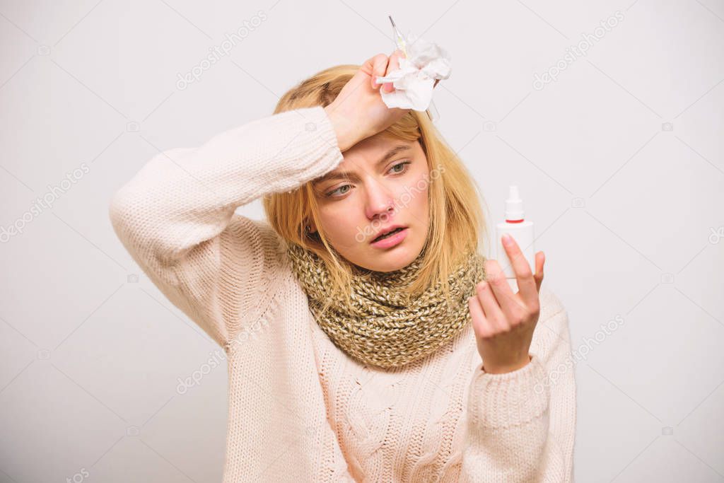 Nasal spray runny nose remedy. Woman feels badly ill sneezing. Girl in scarf hold nasal spray and tissue. Cold and flu remedies. Runny nose and other symptoms of cold. Nasal drops bottle