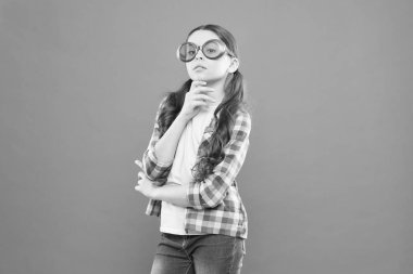 Akıllı ve kendinden emin. Süslü gözlüklerle akıllı bakışları olan sevimli çocuk. Şık küçük çocuk akıllı gözlük takıyor. Turuncu arka planda küçük akıllı kız