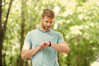 Modern teknoloji. Bilek bandı aleti. Atlet kontrol fitness izci doğa arka plan. Kıllı atlet pedometre gadget ilerleme sonucu bakar. Akıllı saat gadget ile sporcu eğitimi