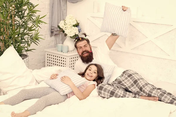 Feliz paternidade. Homem hipster barbudo com penteado infantil pôneis coloridos e filha em pijama. Guy e menina relaxando no quarto. Estilo pijama. A divertir-se numa festa de pijama. Festa da madeira — Fotografia de Stock