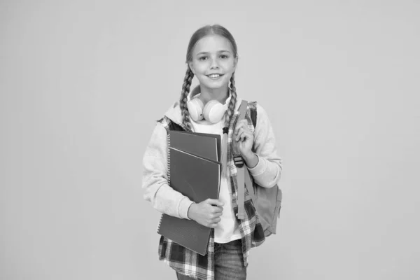 Bonjour l'école. Fille heureuse prête pour l'école sur fond jaune. Un gamin tient des livres et un cartable. Petit enfant de retour à l'école en automne. Éducation et connaissance — Photo