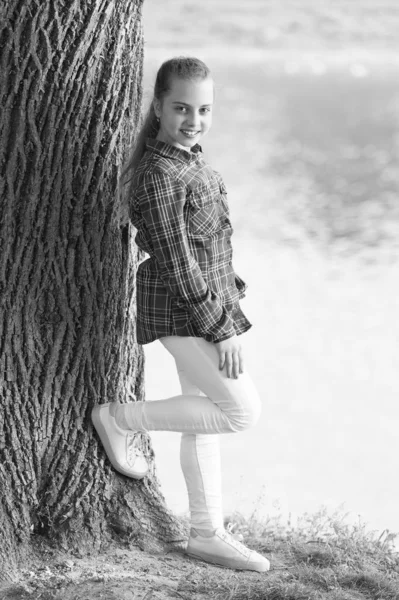 Me siento relajado. Adorable chica con el pelo largo y rubio en estilo casual a cuadros. Niña vistiendo ropa de verano de moda. Niña pequeña con aspecto de belleza. Chica linda de moda en el paisaje natural —  Fotos de Stock