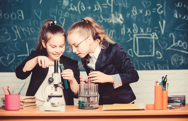 Mikroszkóp és kémcsövek az asztalon. Vegyi reakciókat végrehajtani. Alapismeretek a kémiáról. Tedd érdekessé a kémiát. Oktatási kísérlet koncepció. A lányok kémiát tanulnak. — Stock Fotó