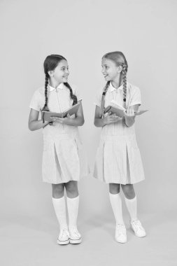 Samimi ilgi. Okul kütüphanesi. Okul için eğitim kitapları. Kitap okuyorum. Okumak ve yeniden anlatmak. Kitapları sarı arka planda tutan küçük çocuklar. Ansiklopedi veya çocuk kitapları ile küçük kızlar