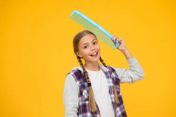 Habilidades peinando el cabello. Niño alegre con cepillo de pelo. Escuela de peluquería. Clases para estilista. Cursos de educación. Cabello enredado. Artículos de peluquería. La chica tiene un peine enorme. Peluquería — Foto de Stock