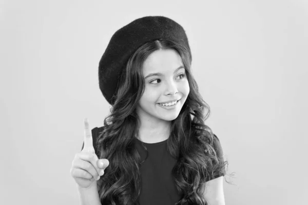 Happy girl with long curly hair in beret. childhood. hairdresser salon. parisian child on yellow background. summer fashion and beauty. little girl in french style hat. great idea for new style — Stock Photo, Image