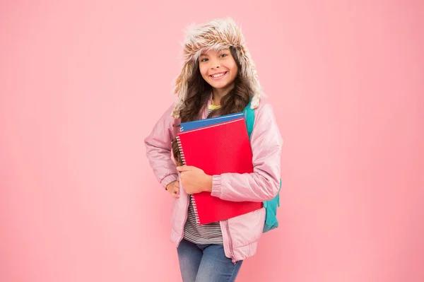 Espera o melhor. de volta à escola. férias de inverno e férias. criança roupas quentes fundo rosa. aluna diário life.schoolgirl levar mochila e livros ir para casa. Não há mais exames. chapéu earflap menina feliz — Fotografia de Stock