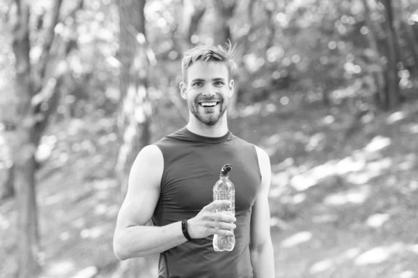 Zdrowy styl życia. Odświeżający napój. Sportowcy trzymają butelkę wody. Sportowiec pije wodę po treningu w parku. Witaminy i minerały. Mężczyzna sportowiec sportowe ubrania dbają o równowagę wodną — Zdjęcie stockowe