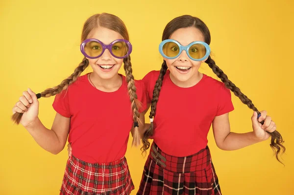 여름 액세서리. 소녀 귀여운 자매 비슷한 의상은 여름 시즌에 화려한 선글라스를 착용합니다. 아이들은 노란색 배경에 선글라스를 끼고 포즈를 취하는 세련된 친구들입니다. 여름 패션 트렌드. 여름의 즐거움 — 스톡 사진