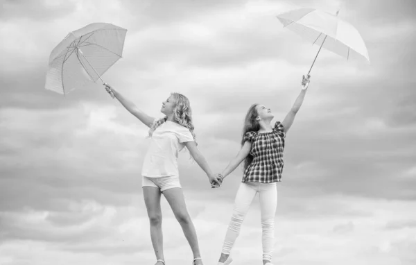 Carefree children outdoors. Girls friends with umbrellas cloudy sky background. Ready for any weather. Windy or rainy we are prepared. Freedom and freshness. Weather forecast. Weather changing — 스톡 사진